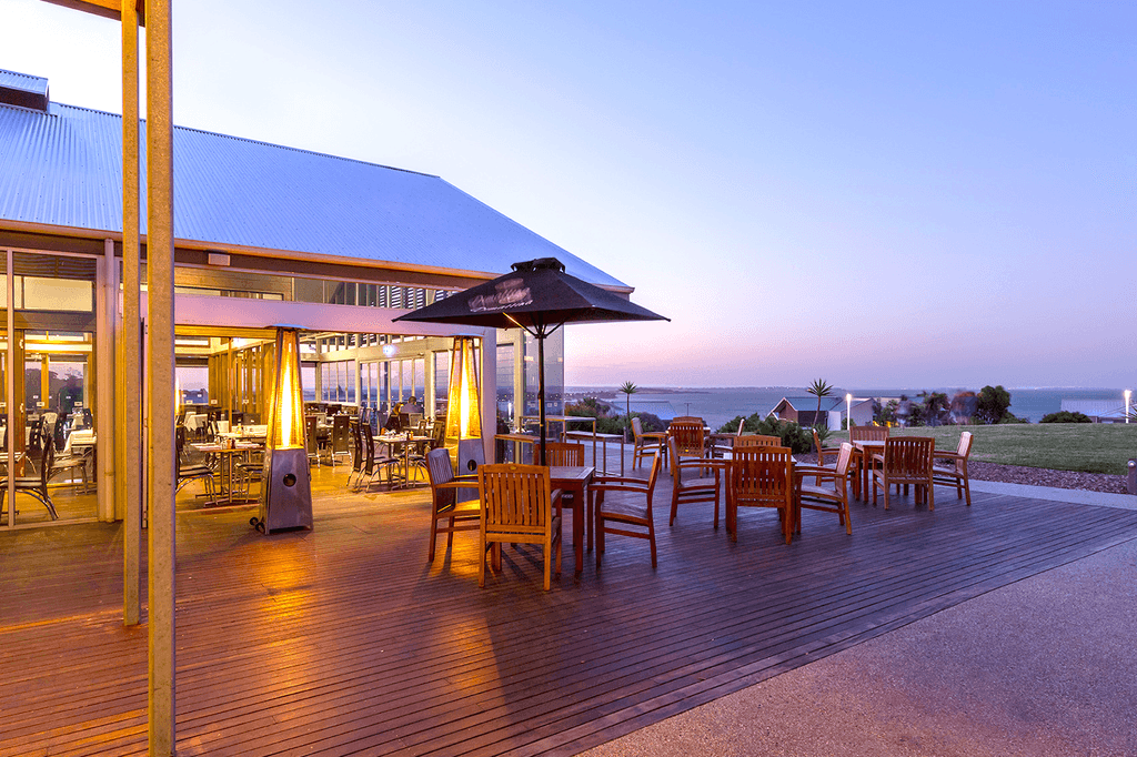 Outdoor dining area with ocean view at Silverwater Resort in San Remo at dusk. 