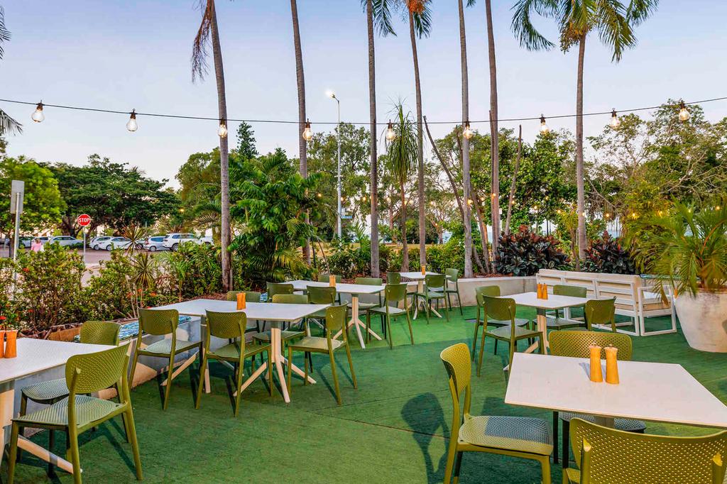 Outdoor dining area at a retreat in Darwin with lush greenery.