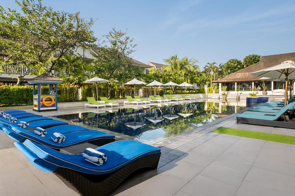Tropical resort pool area with sun loungers and lush greenery in Seminyak.