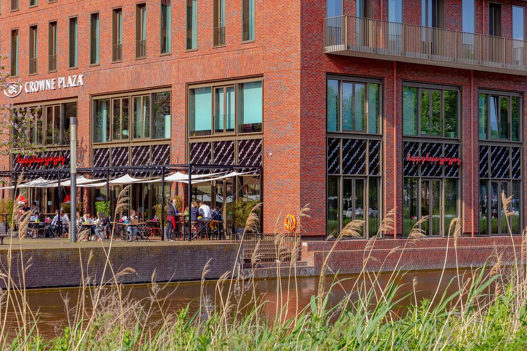 Crowne Plaza Amsterdam by a canal with outdoor dining area.