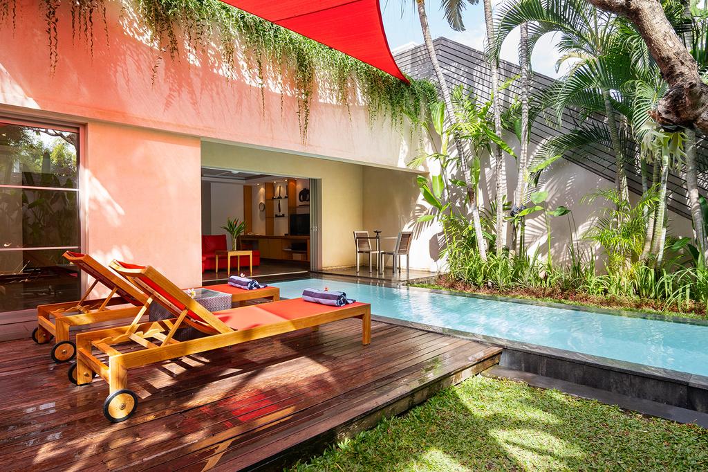 Private villa pool with sun loungers surrounded by greenery in Seminyak.