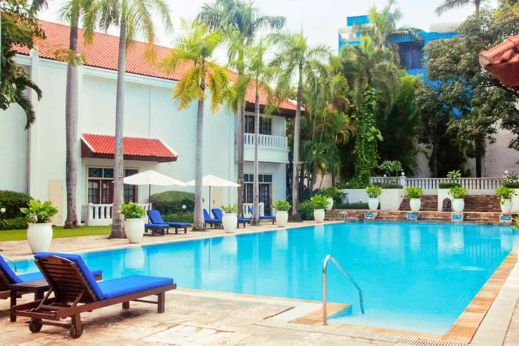 Colonial-style hotel pool area with tropical gardens and sun loungers.