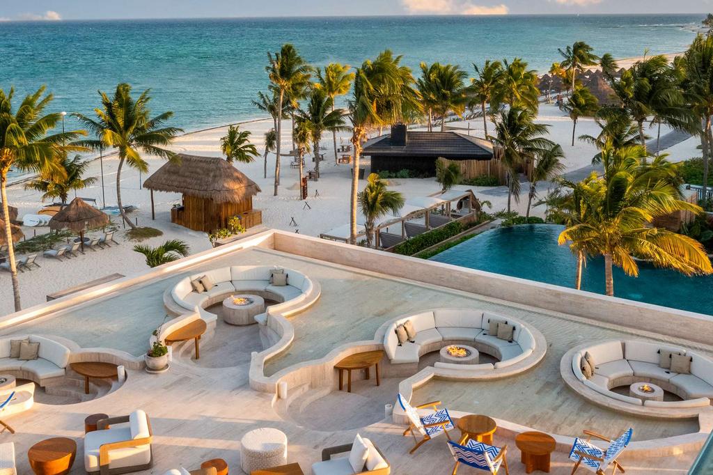 Beachfront resort with palm trees and luxurious seating areas by the ocean.