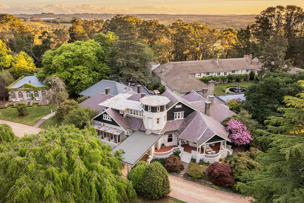 Aerial view of a luxurious estate surrounded by gardens and trees.
