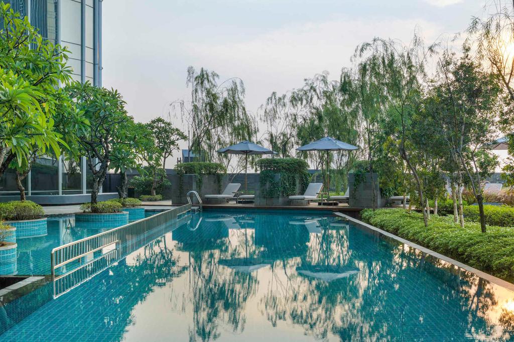 Outdoor pool at Swissôtel Jakarta surrounded by lush greenery.