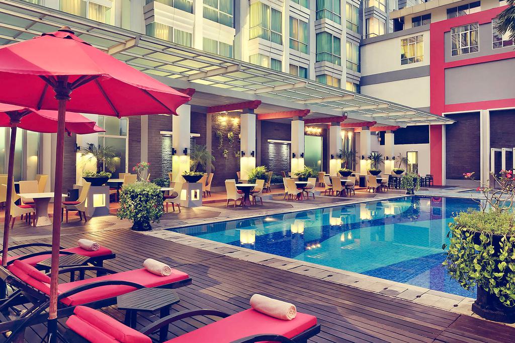 Contemporary hotel with outdoor pool and lounge chairs in Pontianak.
