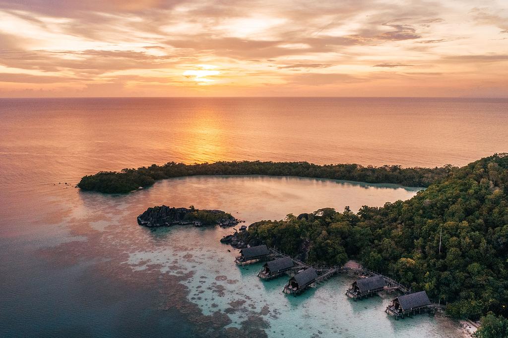A tranquil tropical island resort at sunset in Indonesia's Anambas Archipelago.