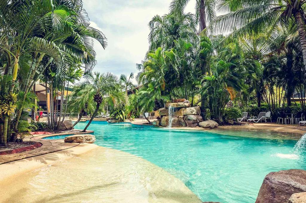 Tropical lagoon-style pool surrounded by lush greenery at a resort.