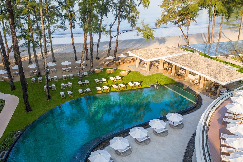 A luxury resort beachfront with a pool and dining area in Phuket.