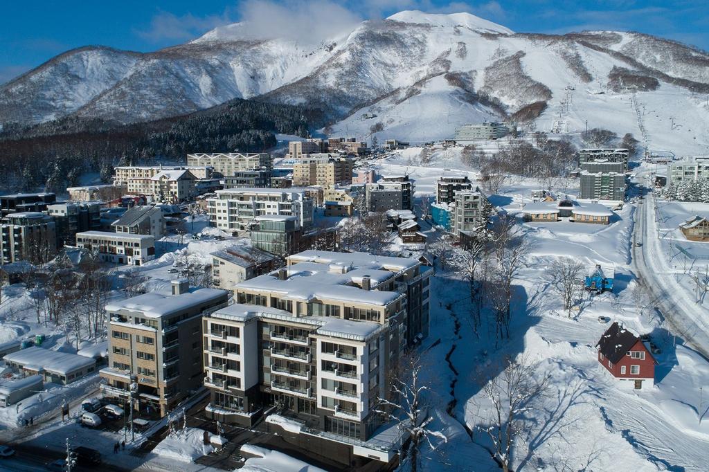 Aerial view of Chatrium Niseko surrounded by snowy mountains in Hirafu Village.