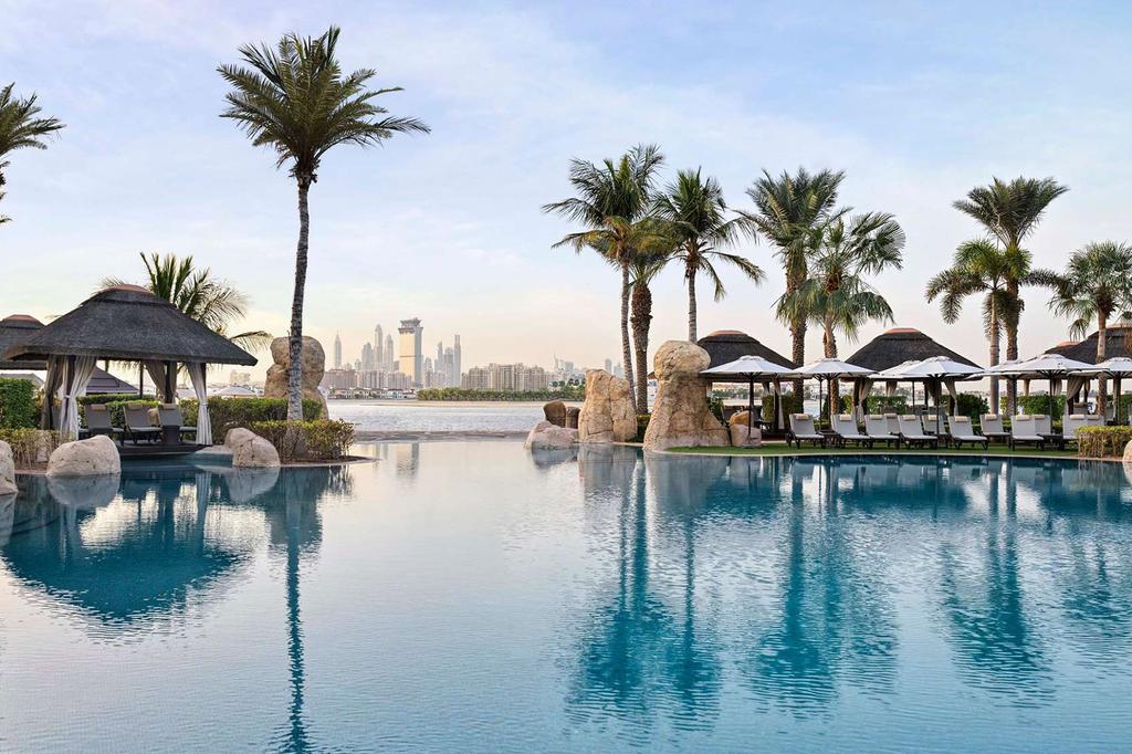 Luxurious pool at Sofitel Dubai The Palm with palm trees and skyline view.