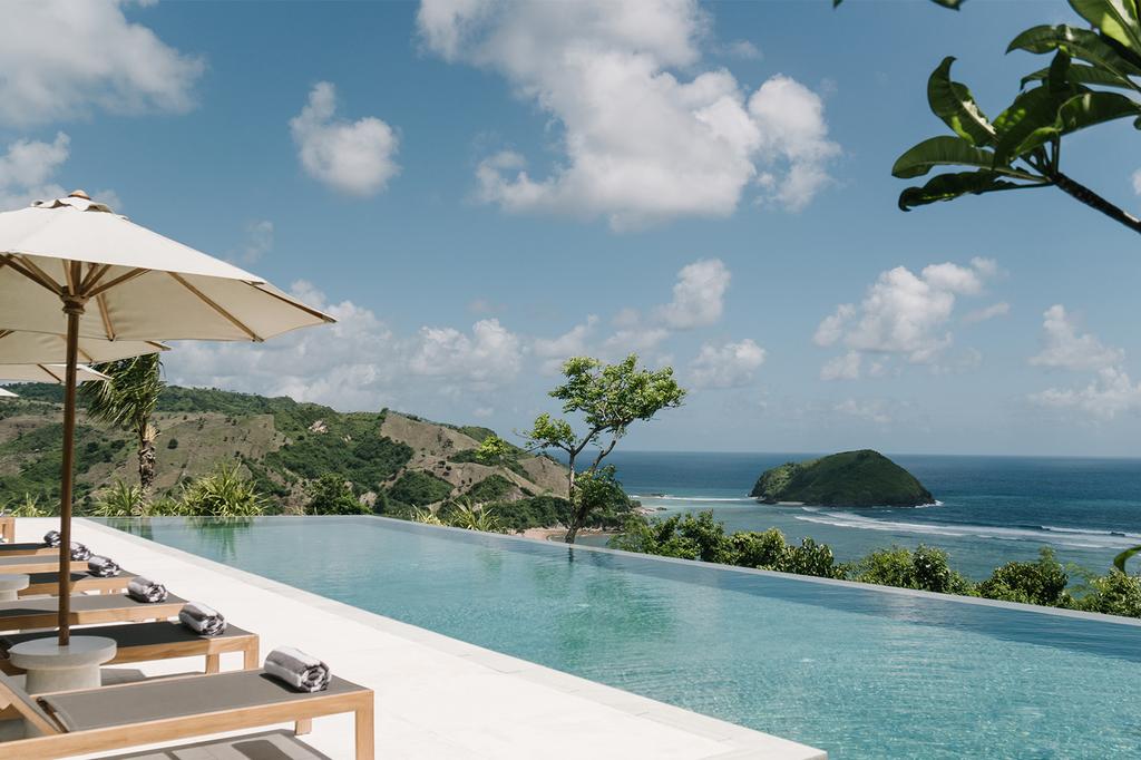 Luxurious Lombok villa with infinity pool overlooking the ocean and lush hills.