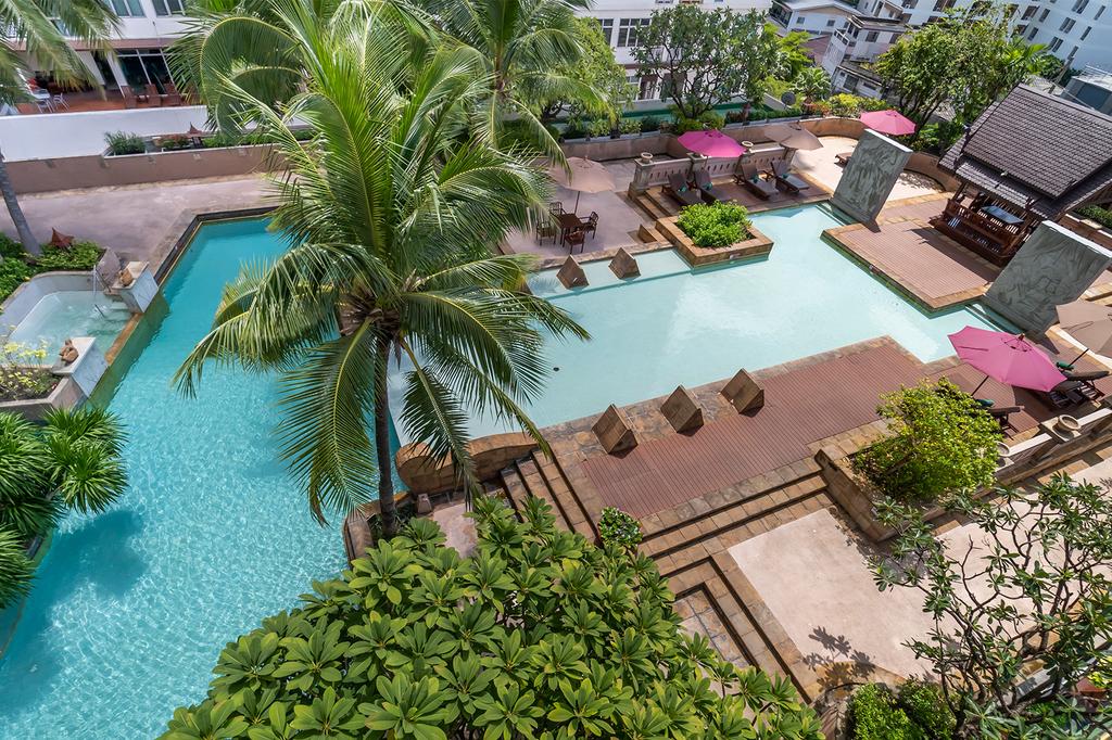 Lagoon-style pool surrounded by lush garden at Century Park Hotel, Bangkok. 