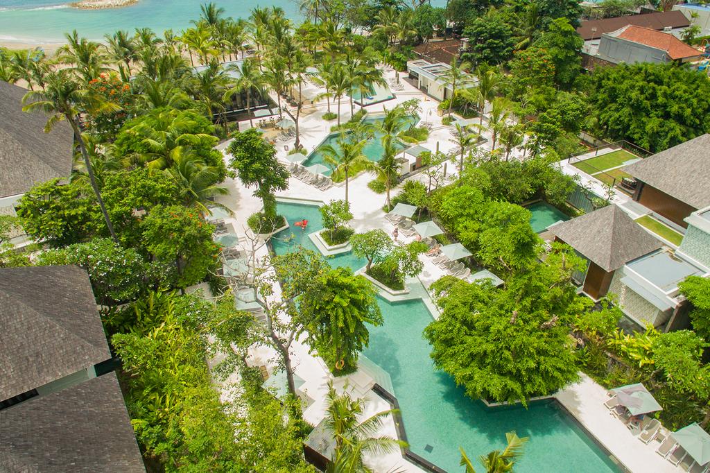 Aerial view of a luxurious Bali beachfront resort with multiple pools and gardens.