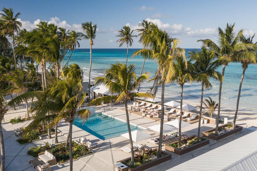 Oceanfront resort in Bahamas with palm trees and a pool area.