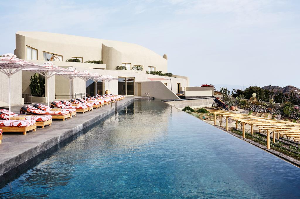 View of a luxurious infinity pool at Andronis Concept Wellness Resort with sun loungers.