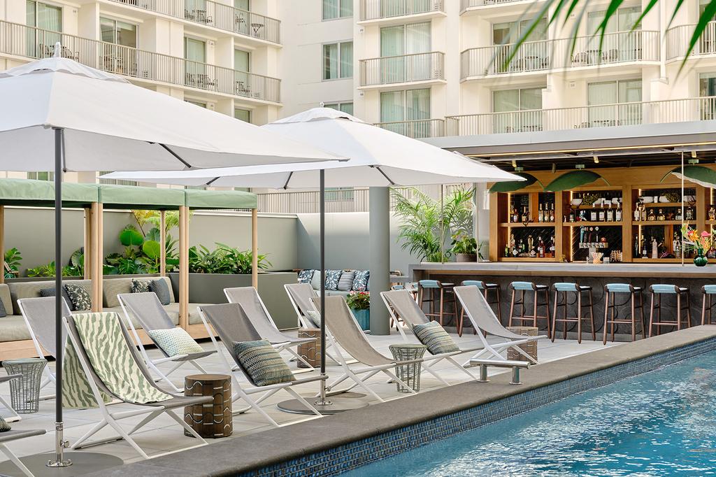 Relaxing pool area at an adults-only Waikiki hotel with sun loungers and a bar.