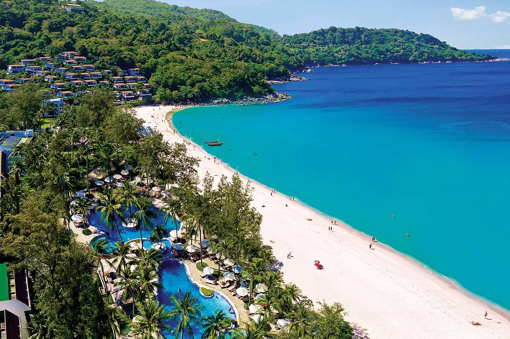 Aerial view of beachfront resort with lush greenery and multiple pools.