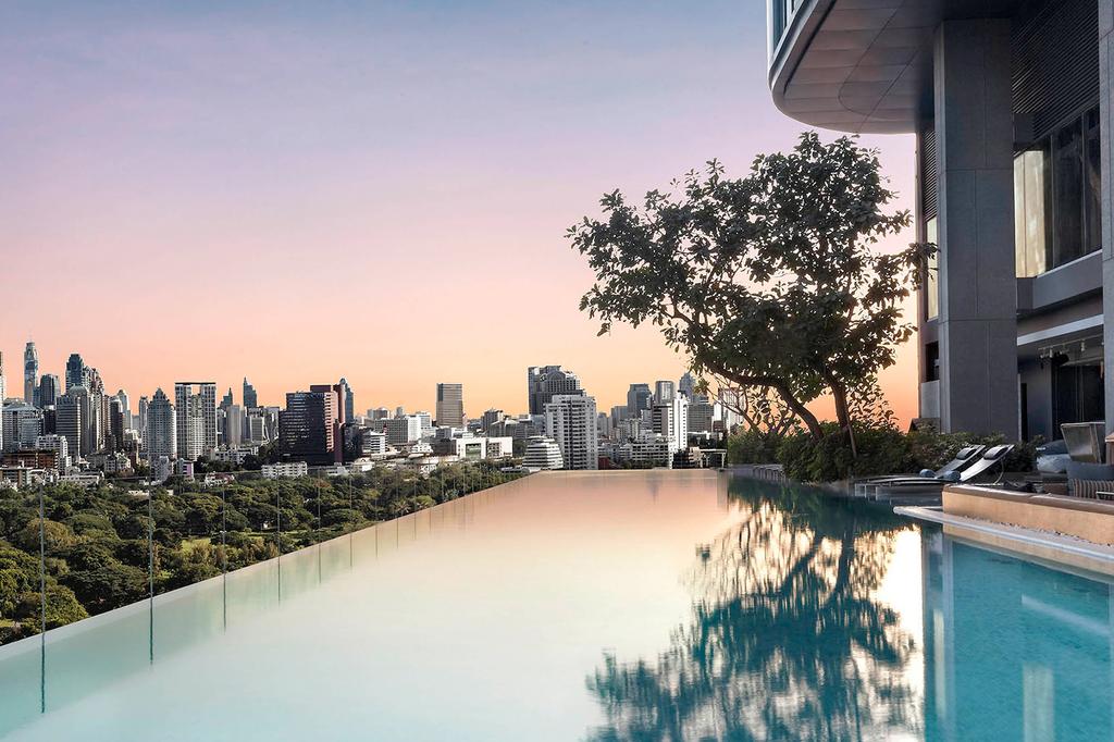 Rooftop infinity pool with stunning city views at sunset in Bangkok hotel.