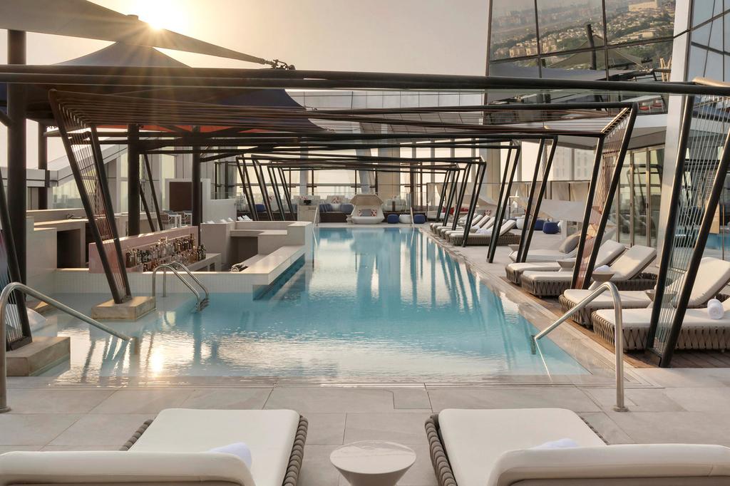 Luxurious rooftop pool bar with skyline views in Dubai hotel.