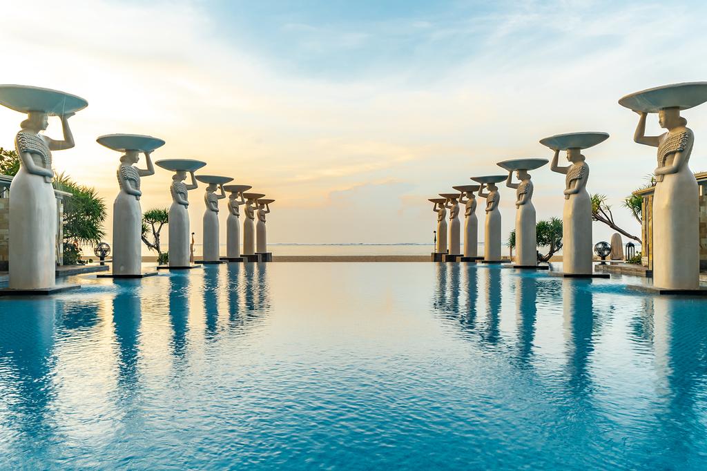 Stunning pool at The Mulia Nusa Dua with ocean view and statues.
