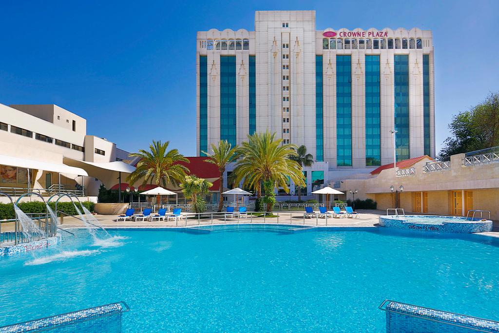 Crowne Plaza Amman with a sparkling outdoor pool and palm trees.