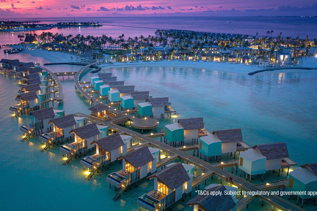 Aerial view of Hard Rock Maldives' overwater bungalows at sunset. 