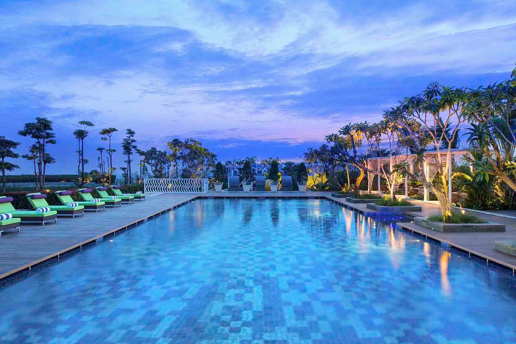 Rooftop garden pool at Novotel Tangerang with surrounding greenery at dusk.