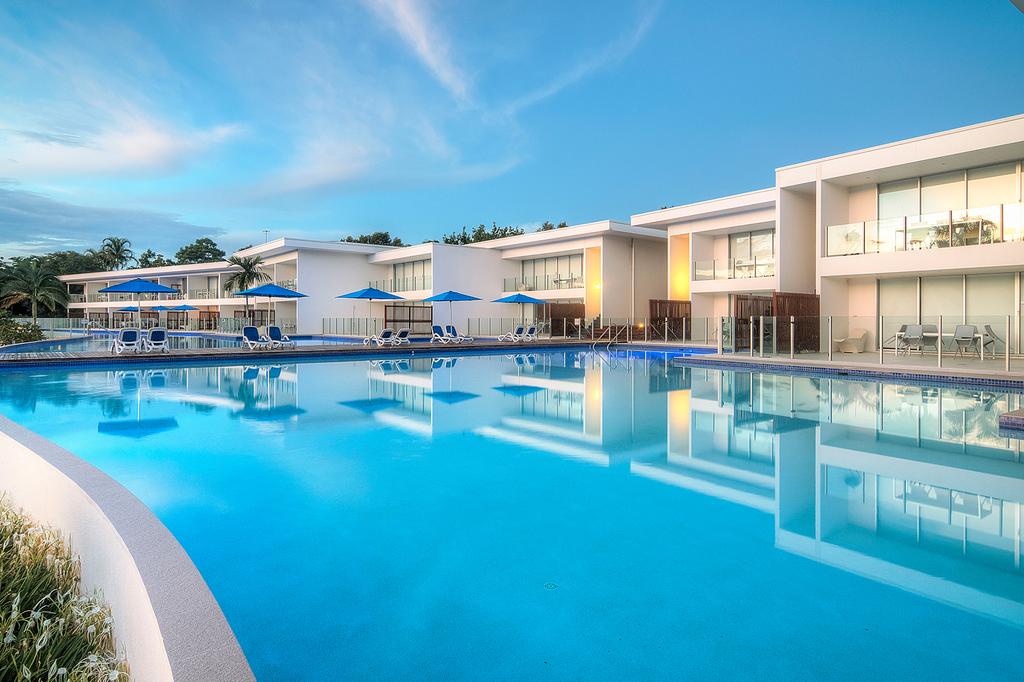 Lagoon pool at Pool Resort Port Douglas with modern apartments and palm trees.