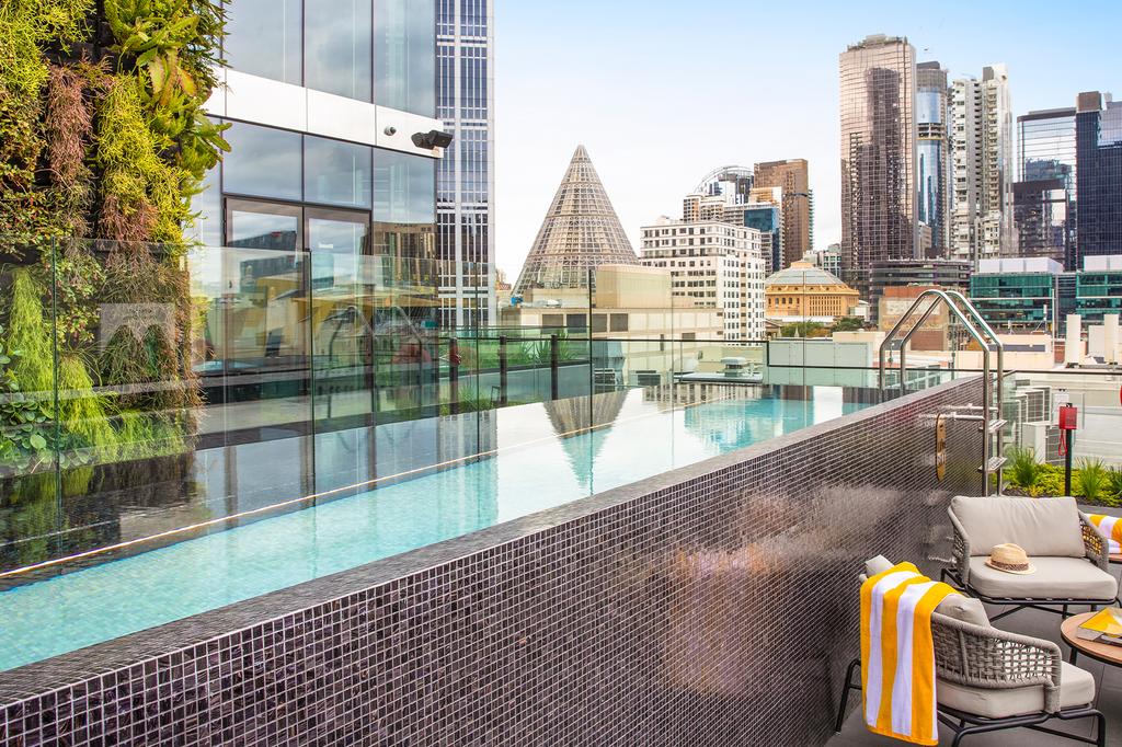 Rooftop swimming pool with city skyline view at voco Melbourne Central.