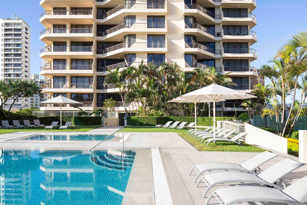 Modern apartment building with pool and sun loungers in Surfers Paradise.