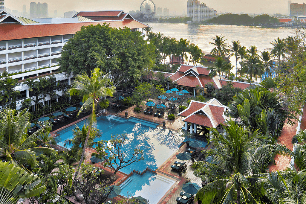 Luxurious riverside resort with pool amidst lush greenery in Bangkok. 