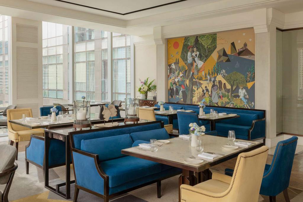 Elegant dining area at Raffles Manila with blue seating and wall mural.
