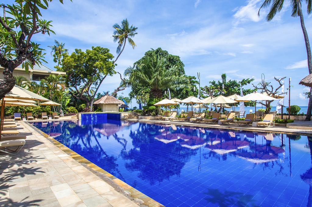 Luxurious beachfront resort in Bali with pool and tropical scenery.
