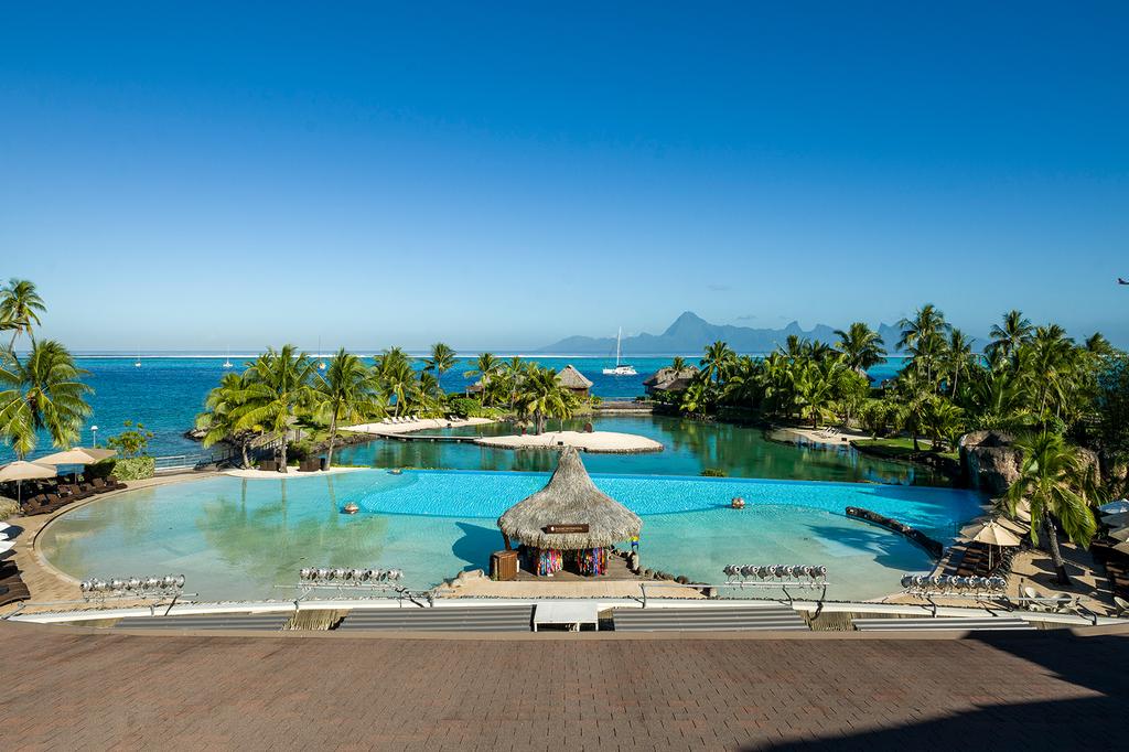 Tahitian resort with pool and ocean view overlooking volcanic peaks.