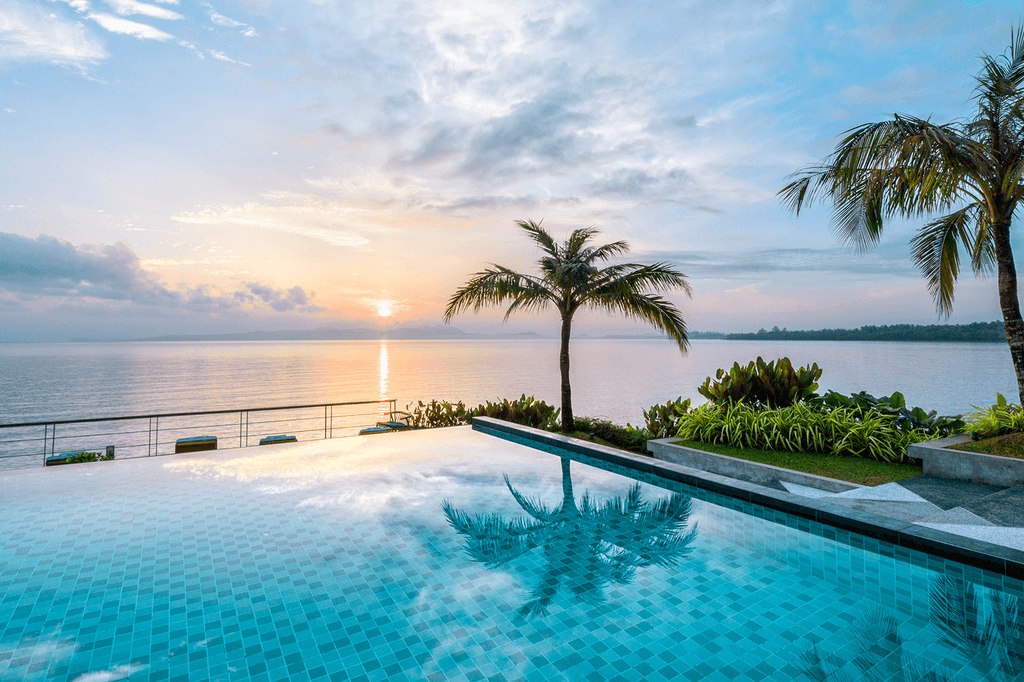 Infinity pool at Cove 55 overlooking ocean at sunset with palm trees in view.