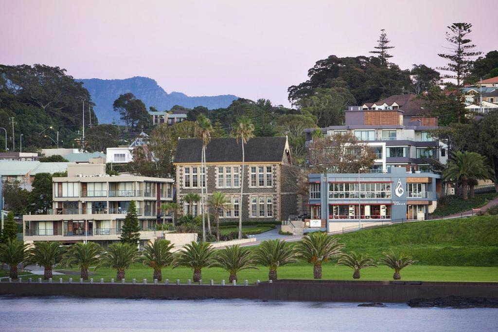 View of Kiama Harbourside Hotel with lush surroundings and palm trees.