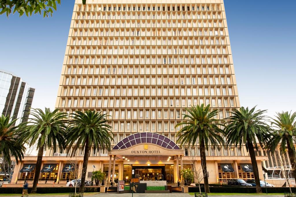 Grand exterior of Duxton Hotel Perth with palm trees.