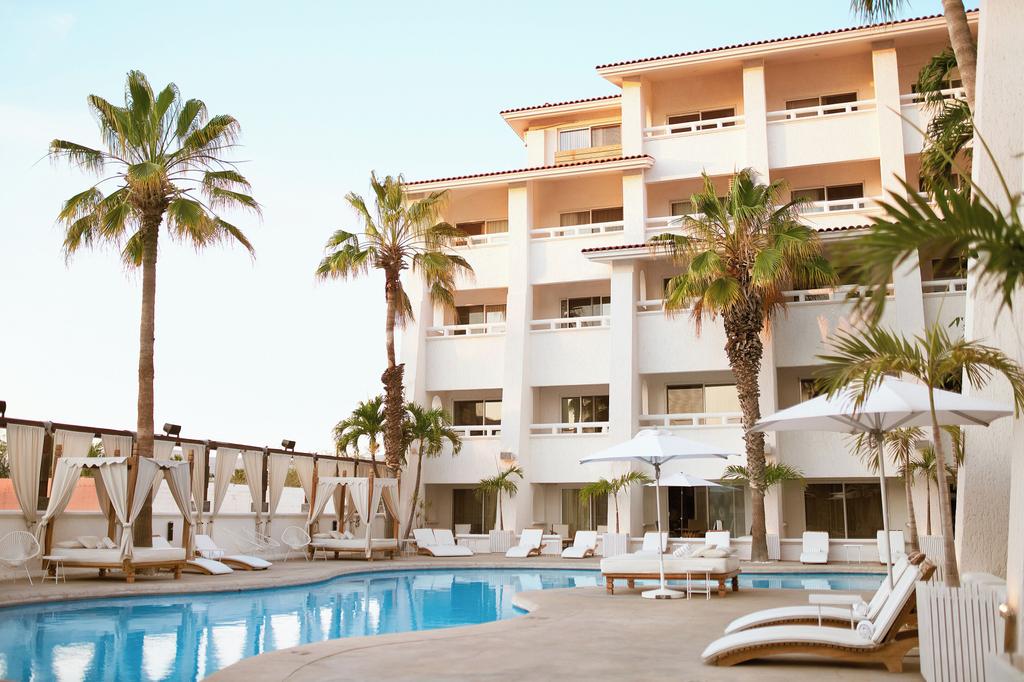 Luxurious hotel with pool and palm trees in Los Cabos.