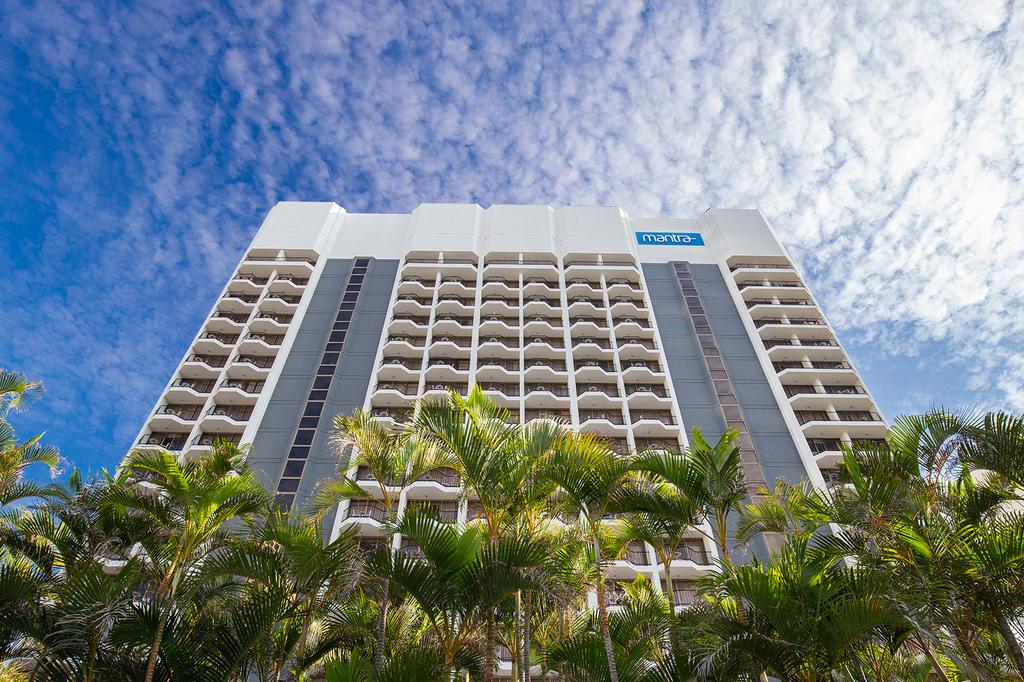 Mantra on View hotel exterior with palm trees and blue sky.