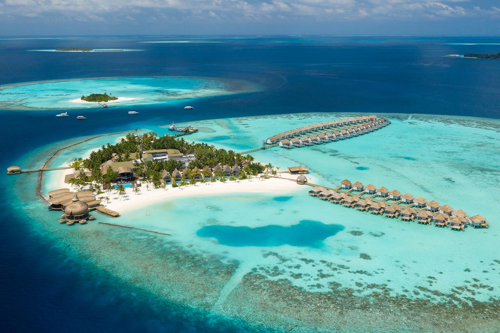 Aerial view of OUTRIGGER Maldives Maafushivaru Resort with overwater villas and turquoise waters. 