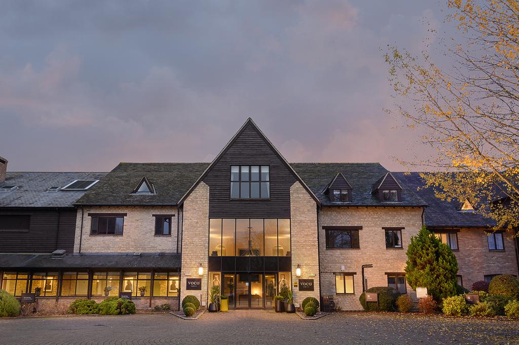Exterior view of voco Oxford Spires hotel at dusk.