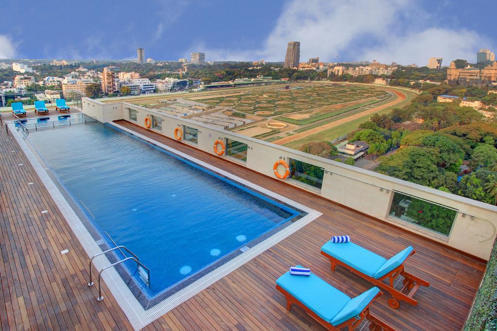 Rooftop pool at Holiday Inn Bengaluru overlooking a racecourse and cityscape.
