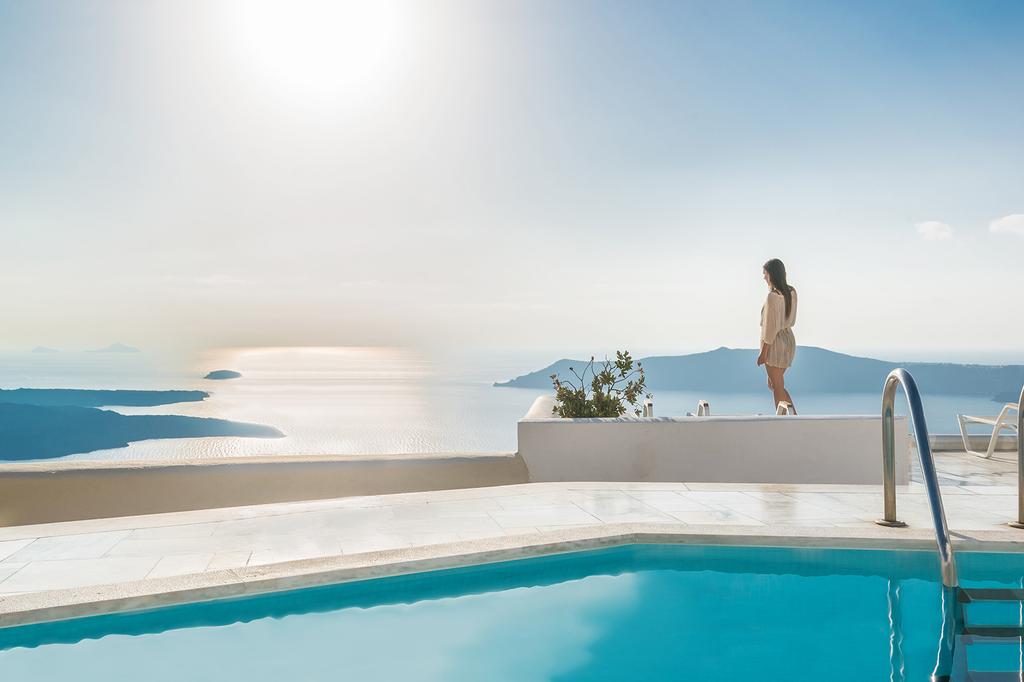 Woman enjoying ocean view from Santorini clifftop poolside at Iliovasilema Hotel & Suites.