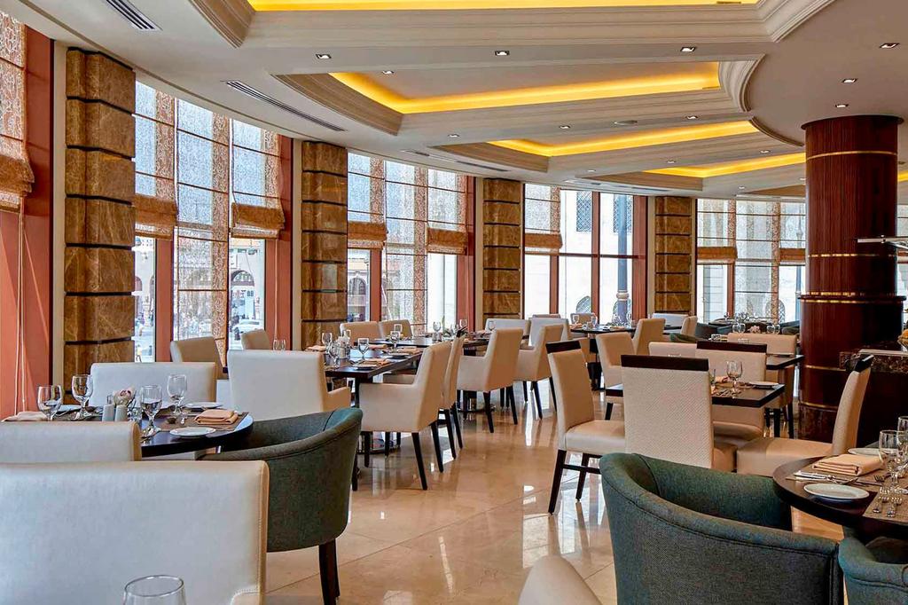 Elegant dining area at Pullman Madinah with large windows and plush seating.