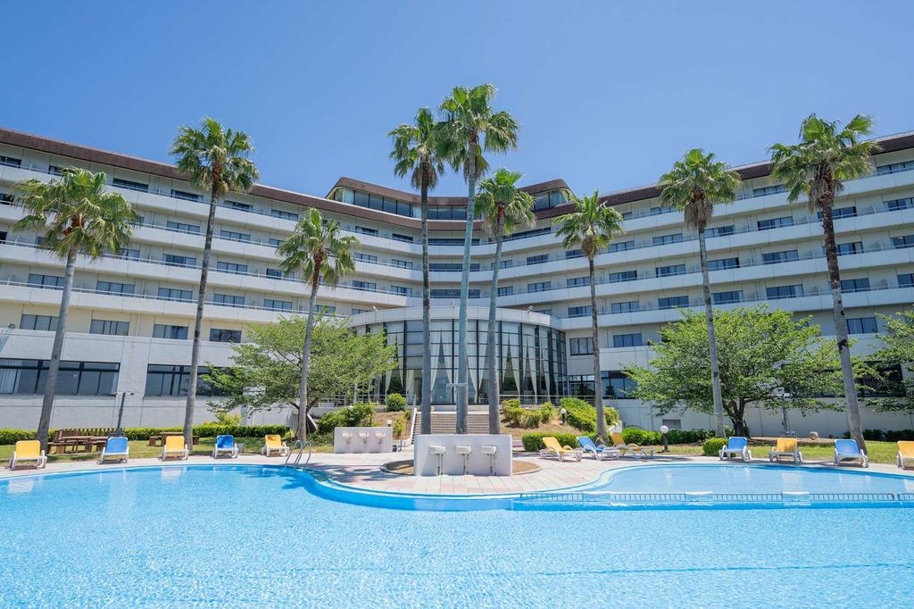 Resort on Awaji Island with outdoor pool surrounded by palm trees.