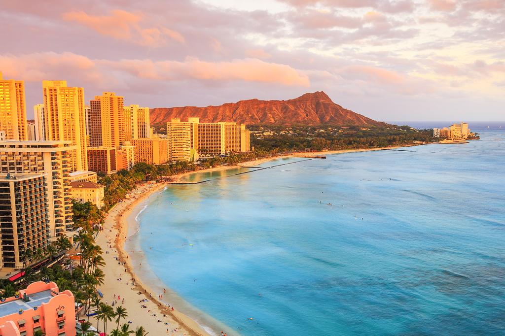 Waikiki Beach with skyline and Diamond Head at sunset.