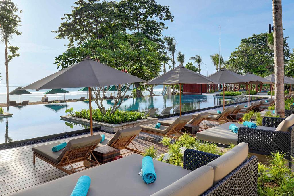 Lush resort pool area with sun loungers and umbrellas by the beachfront.