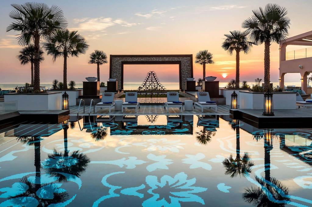 Luxurious pool area at UAE beachfront resort during sunset.