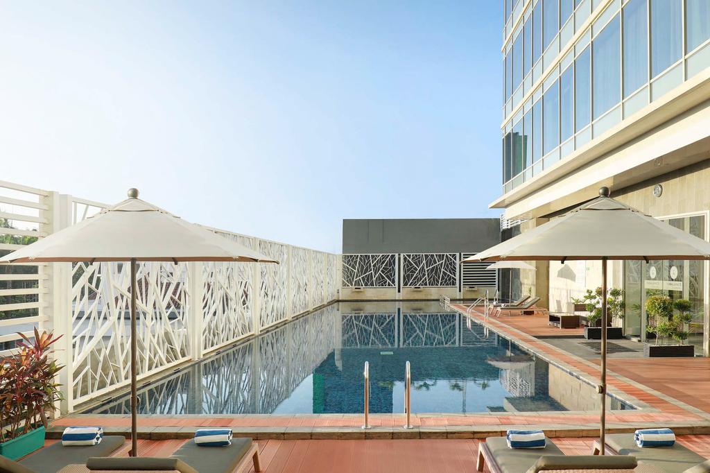 Modern hotel pool with sun loungers and umbrellas in Makassar.